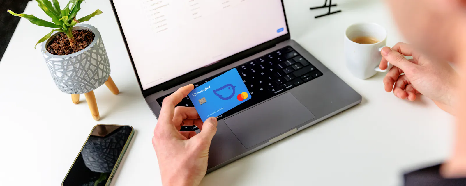 Koffie met mobiele telefoon en betaalpas bij laptop met handen