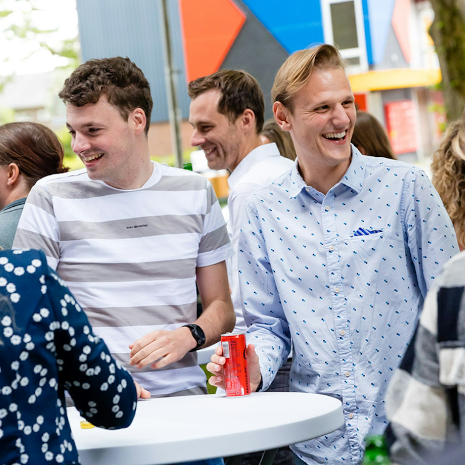 Collgea's buiten naast het pand tijdens borrel waarbij Marijn naar een collega lacht