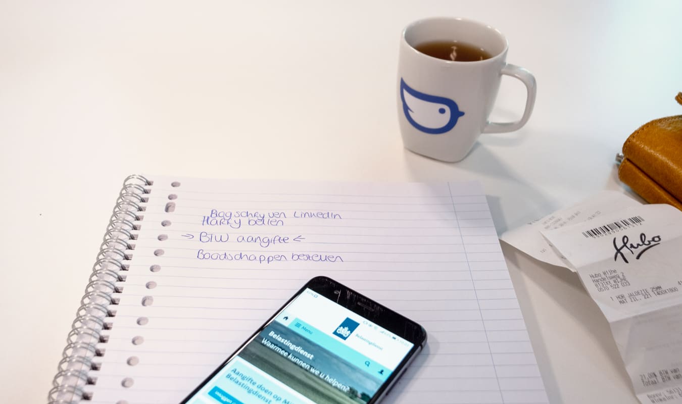 Een kladblok, telefoon en kopje koffie