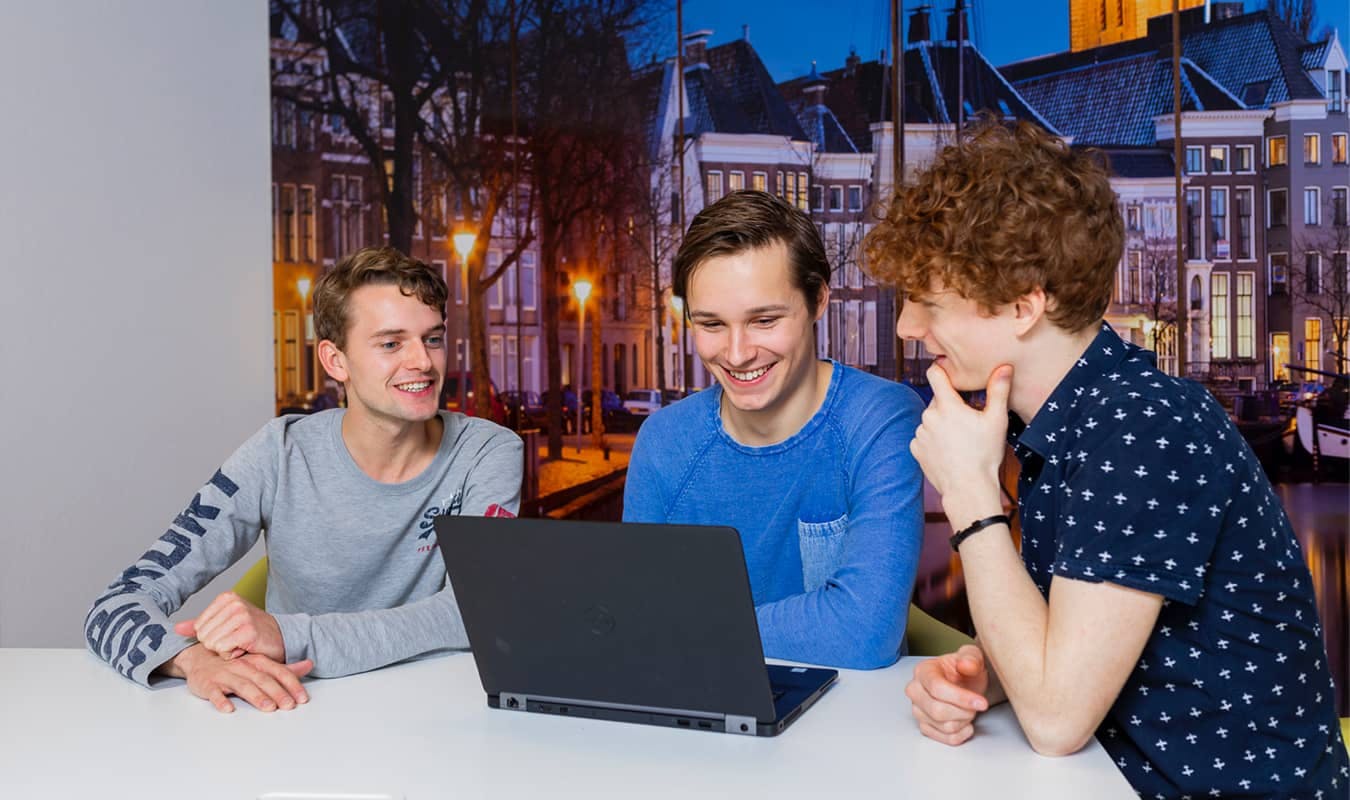 Drie mensen kijken naar een laptopscherm