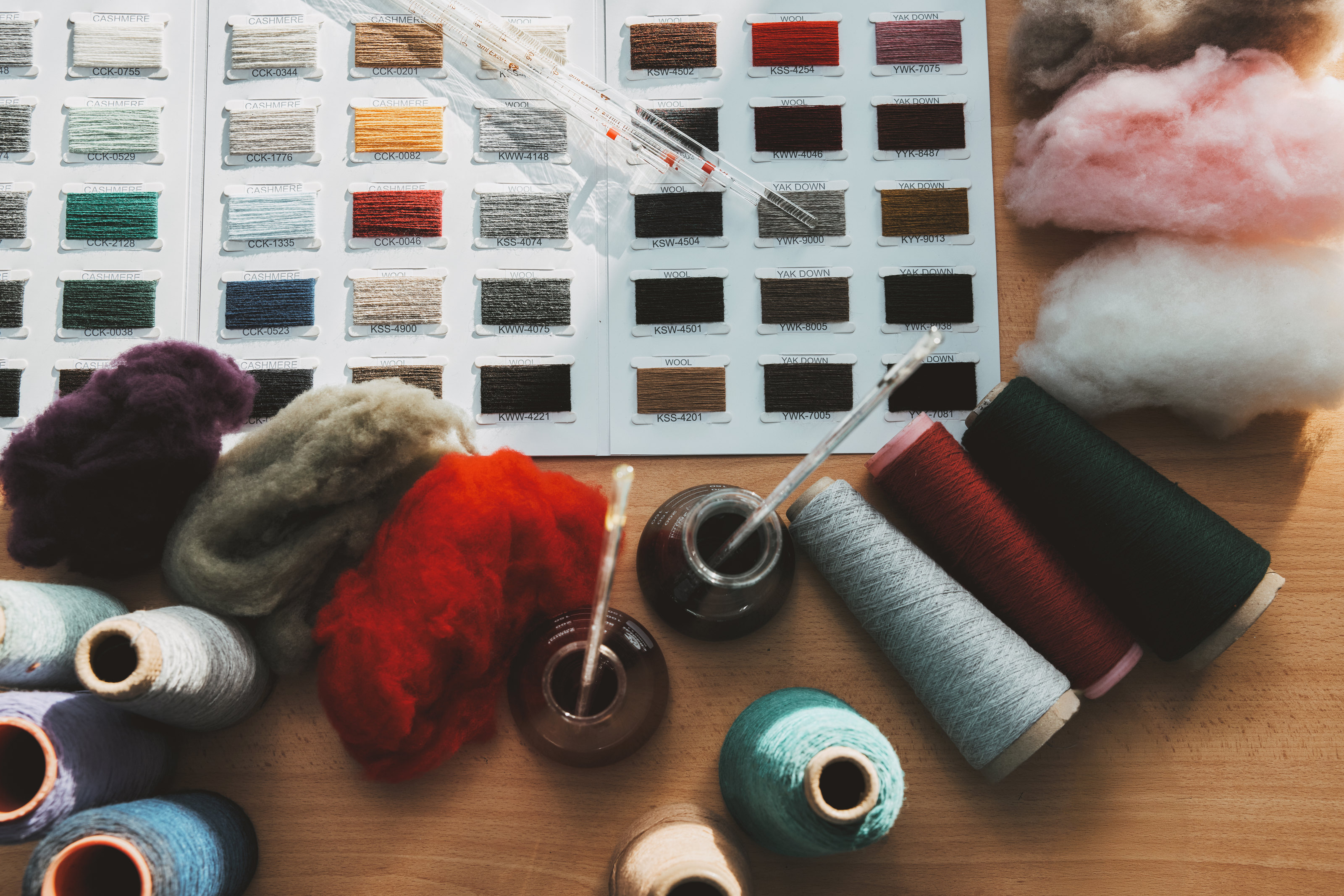 Colour swatches, loose fibre and yarn laid out on a worktable.