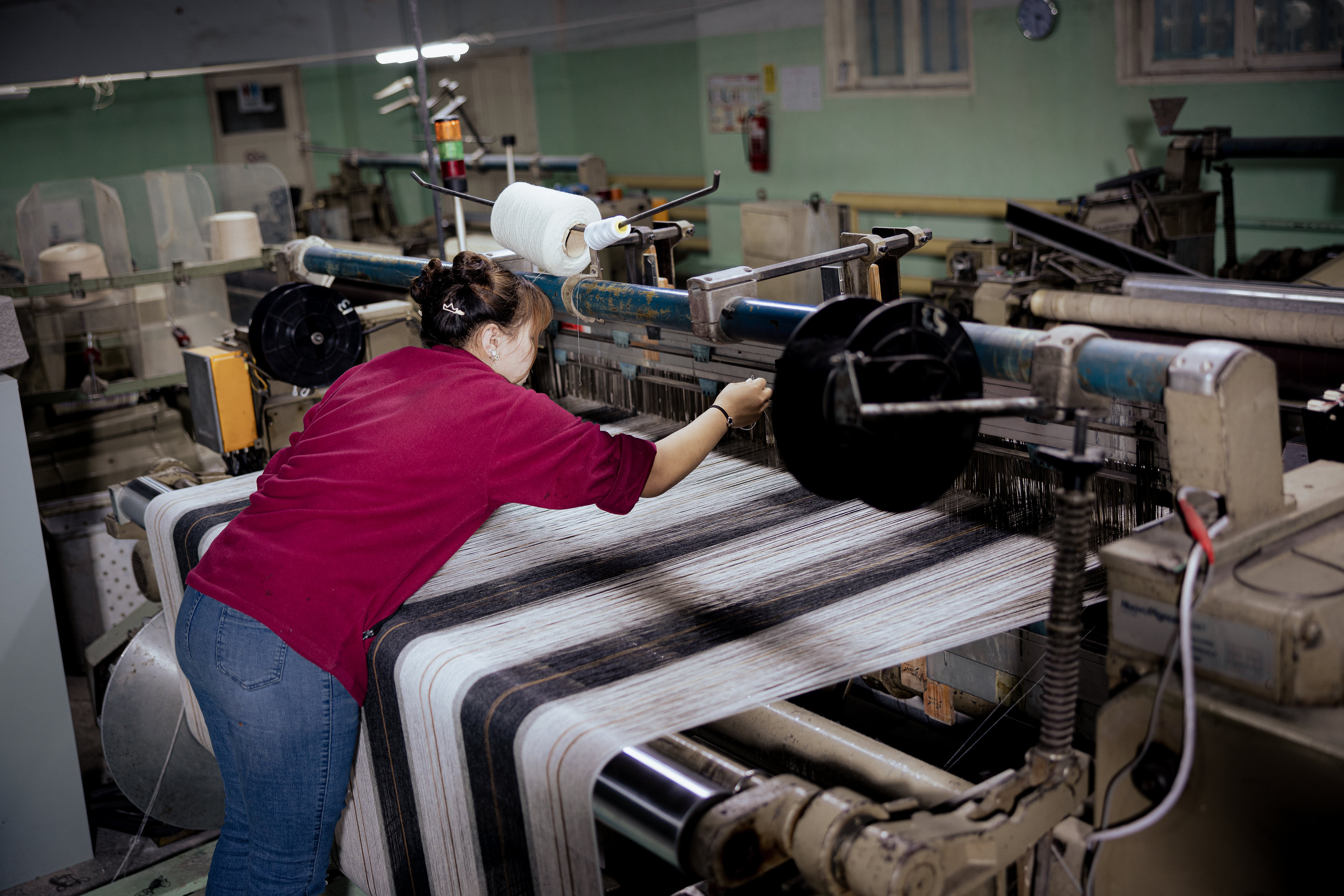 An operator beside striped textile on a loom.
