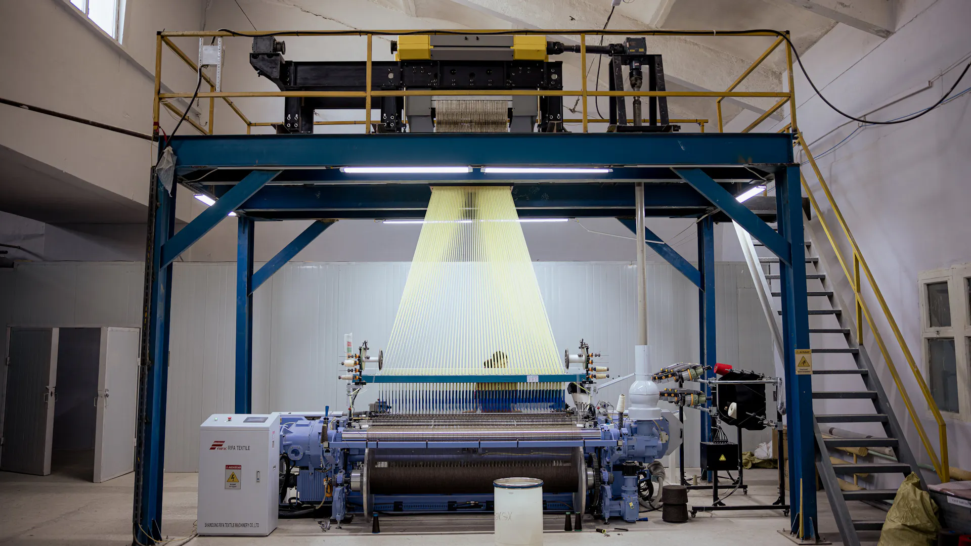 Wide view of a large loom inside a workroom.