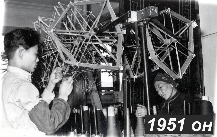 Black-and-white archive photograph of people beside yarn reels.