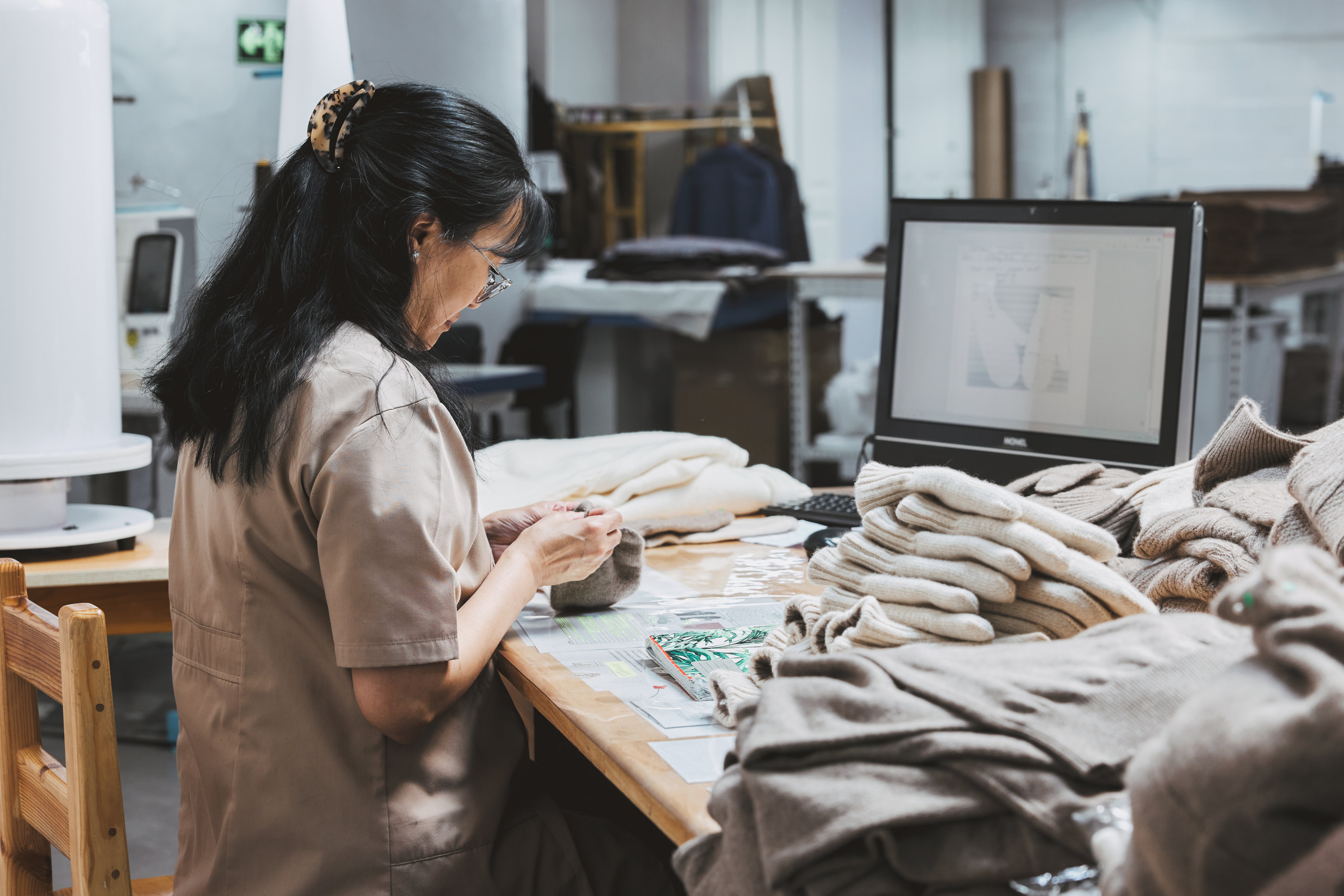 Employees examining knitted garments at a work table.