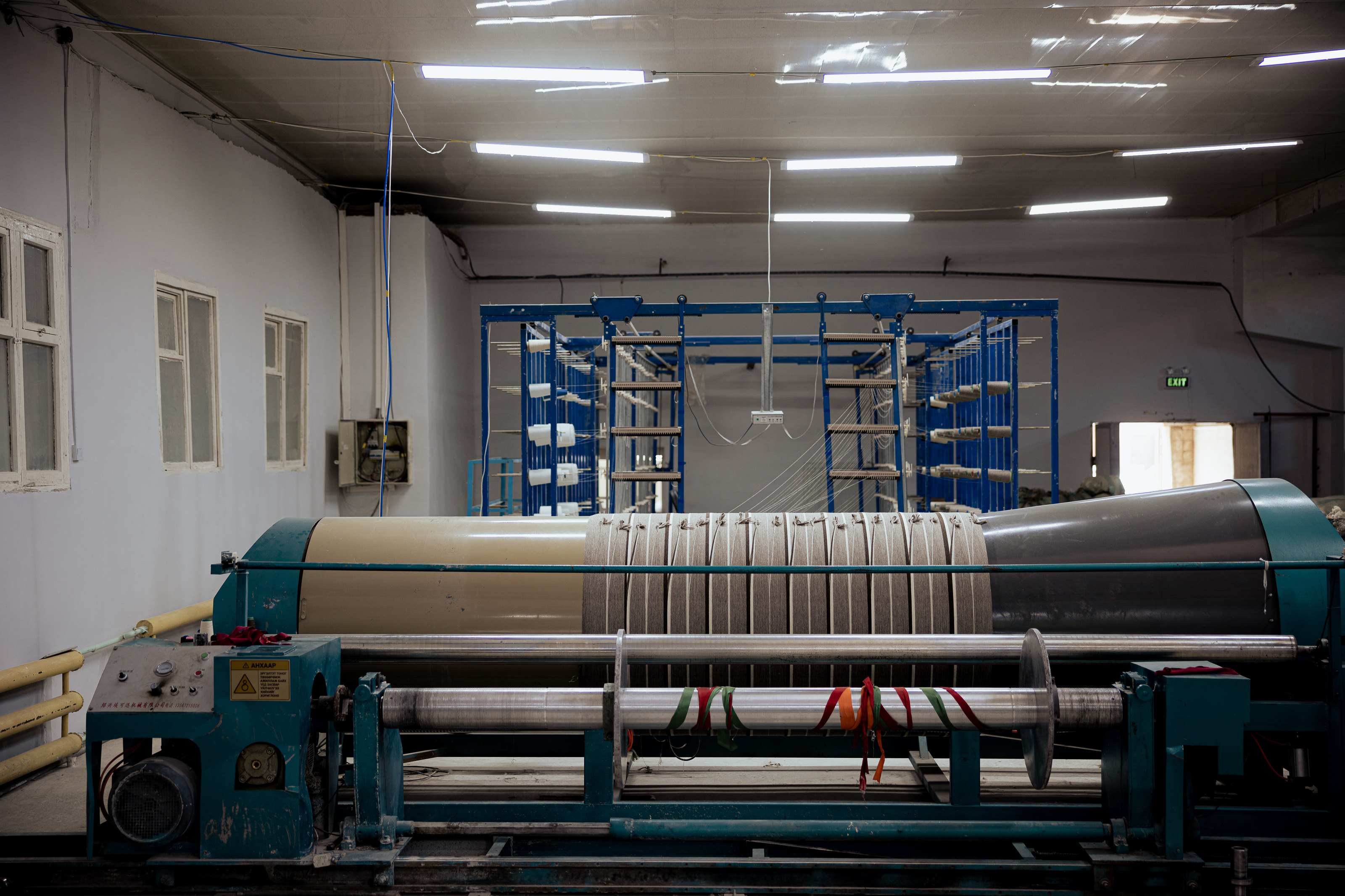 Textile machinery with broad rollers inside a workroom.