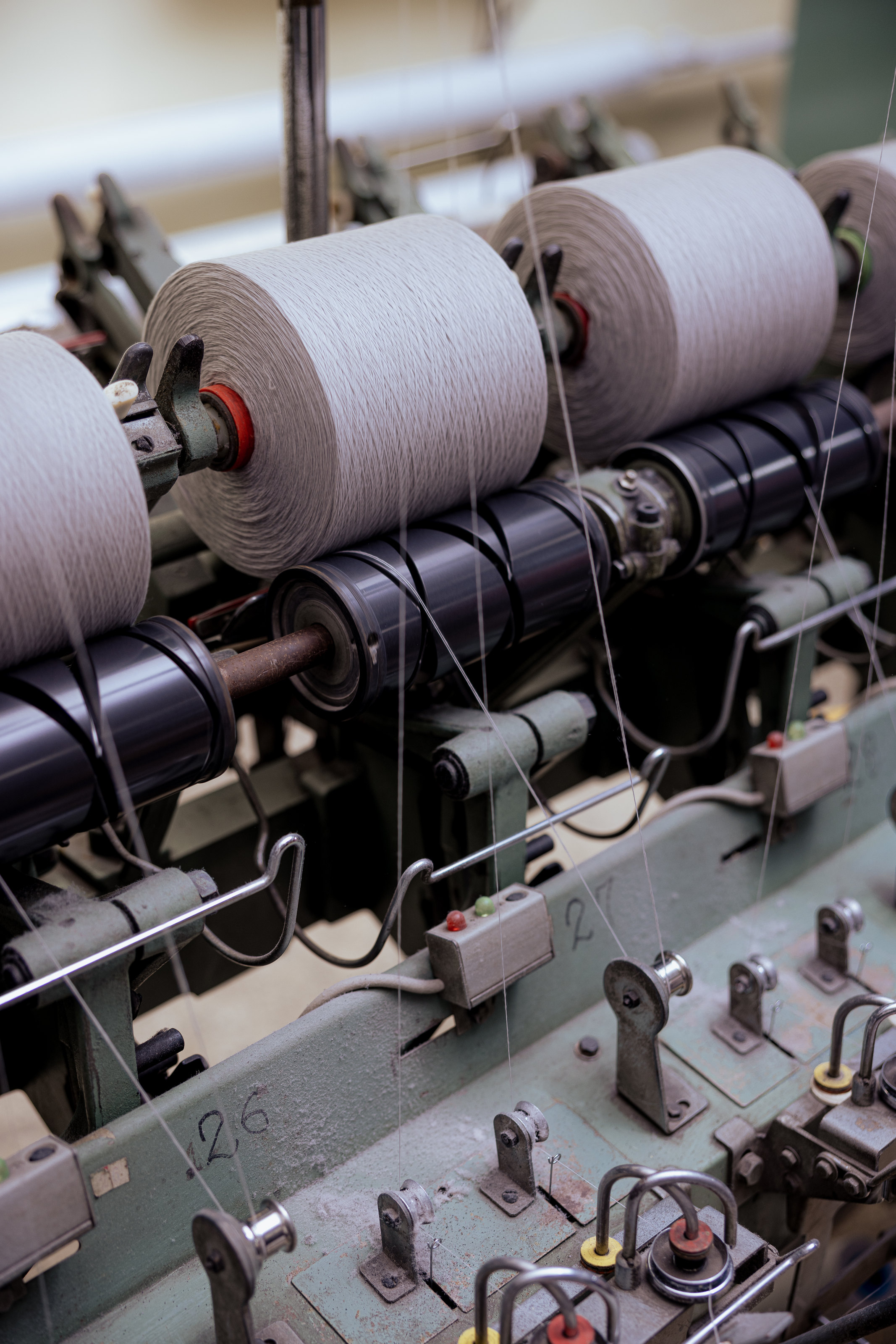 Light-coloured yarn packages mounted on machine holders.