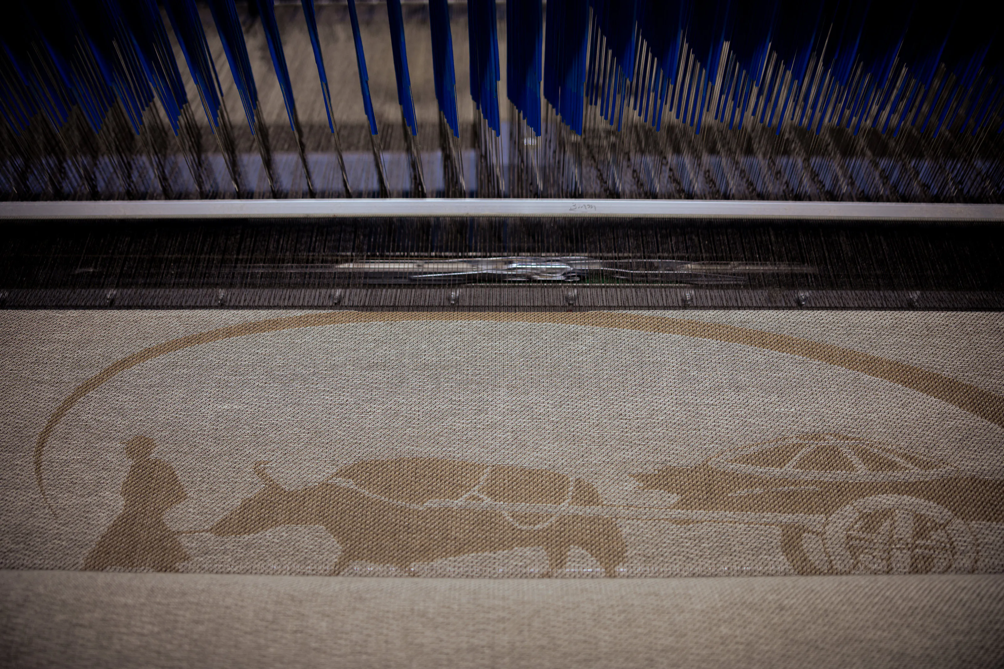 A patterned textile beneath the threads of a loom.