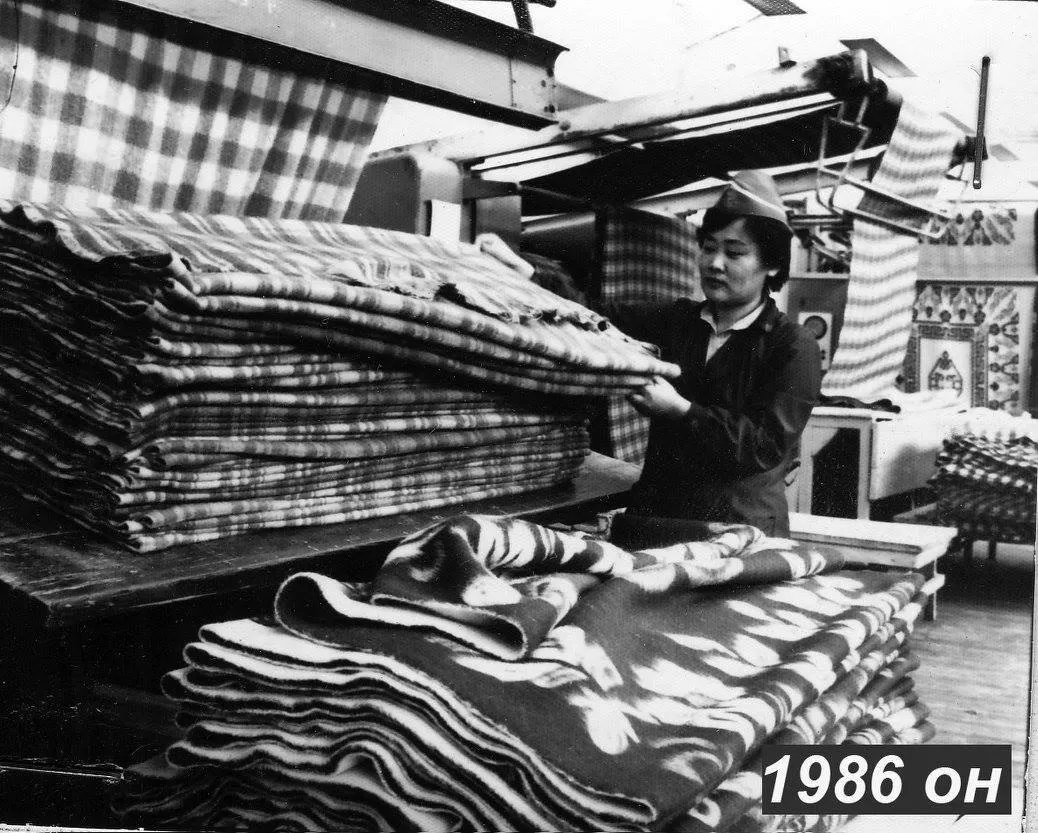 Archive photograph of an employee holding folded patterned textiles.