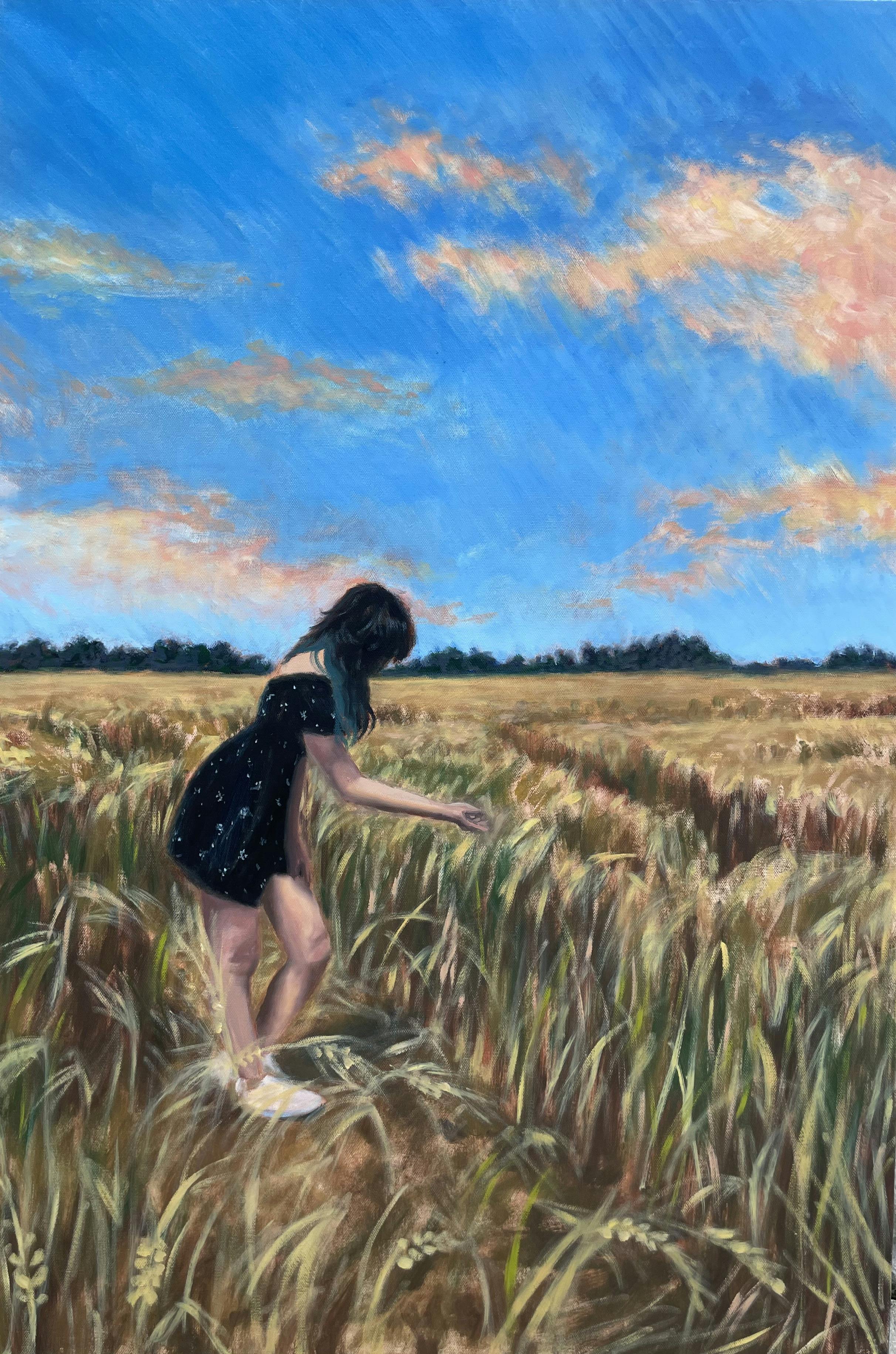 woman reaching down touching wheat in a wheat field