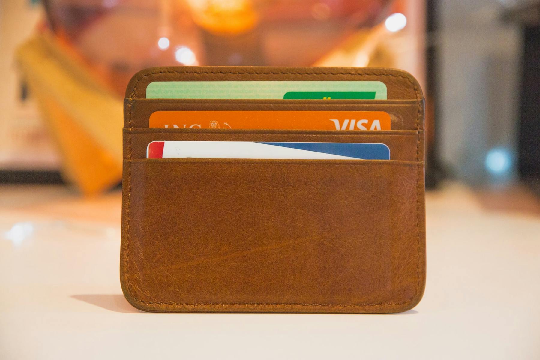 Carteira de couro marrom com três cartões de crédito nas divisórias