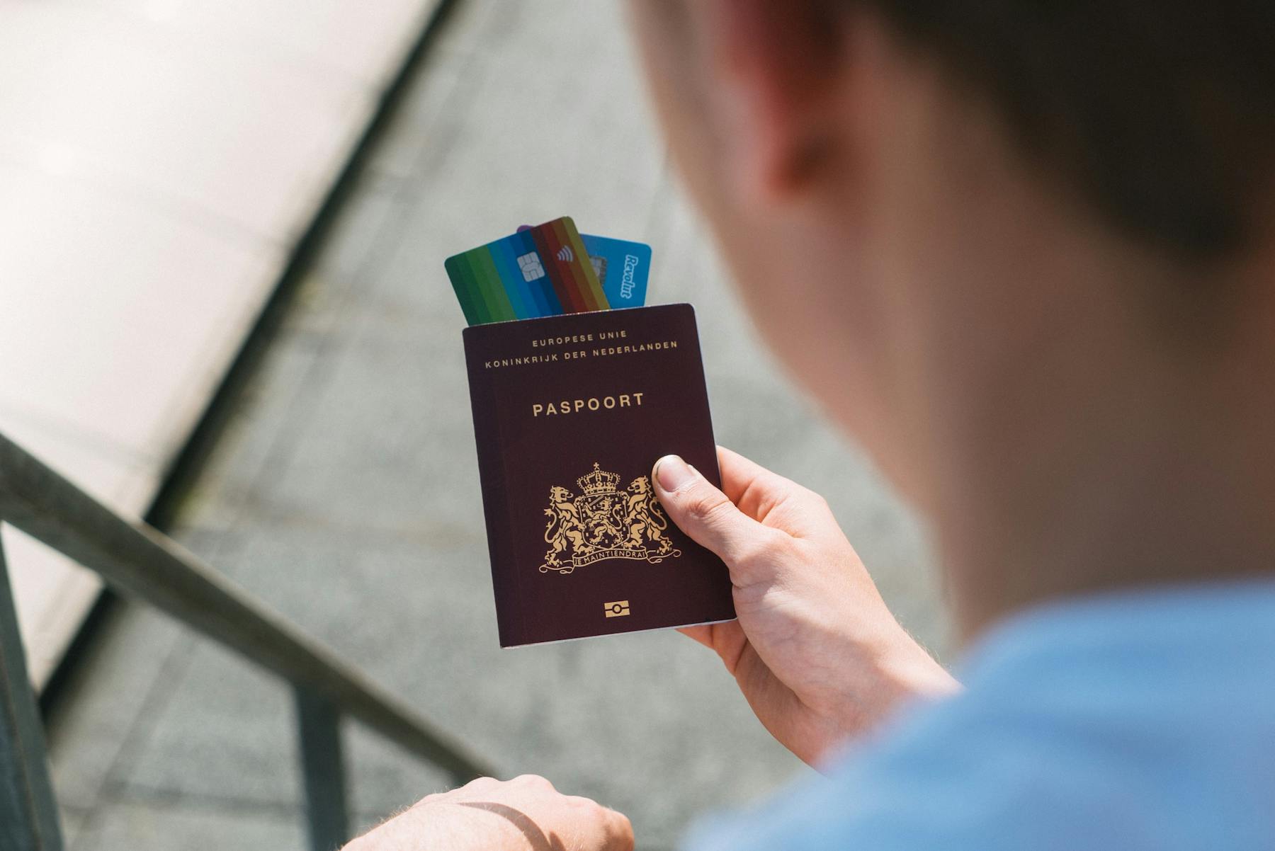 Homem segura na mão seu passaporte e cartões de banco