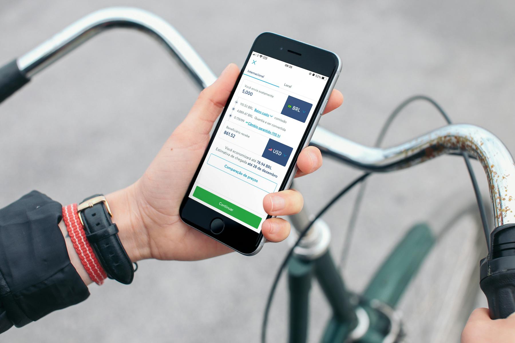 Homem em uma bicicleta segura seu celular e olha aplicativo da Wise