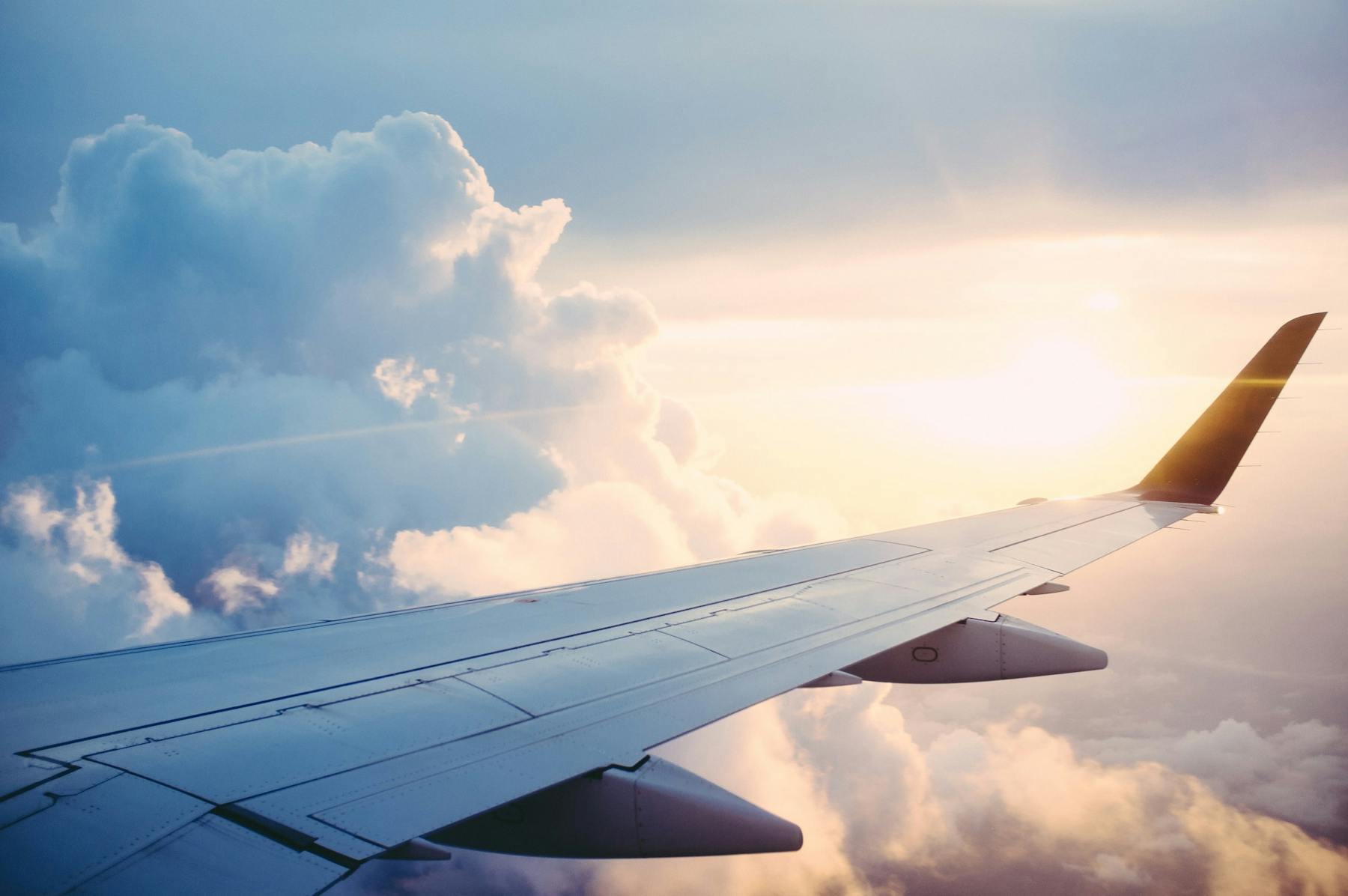 The wing of a commercial aircraft in the clouds during a flight.