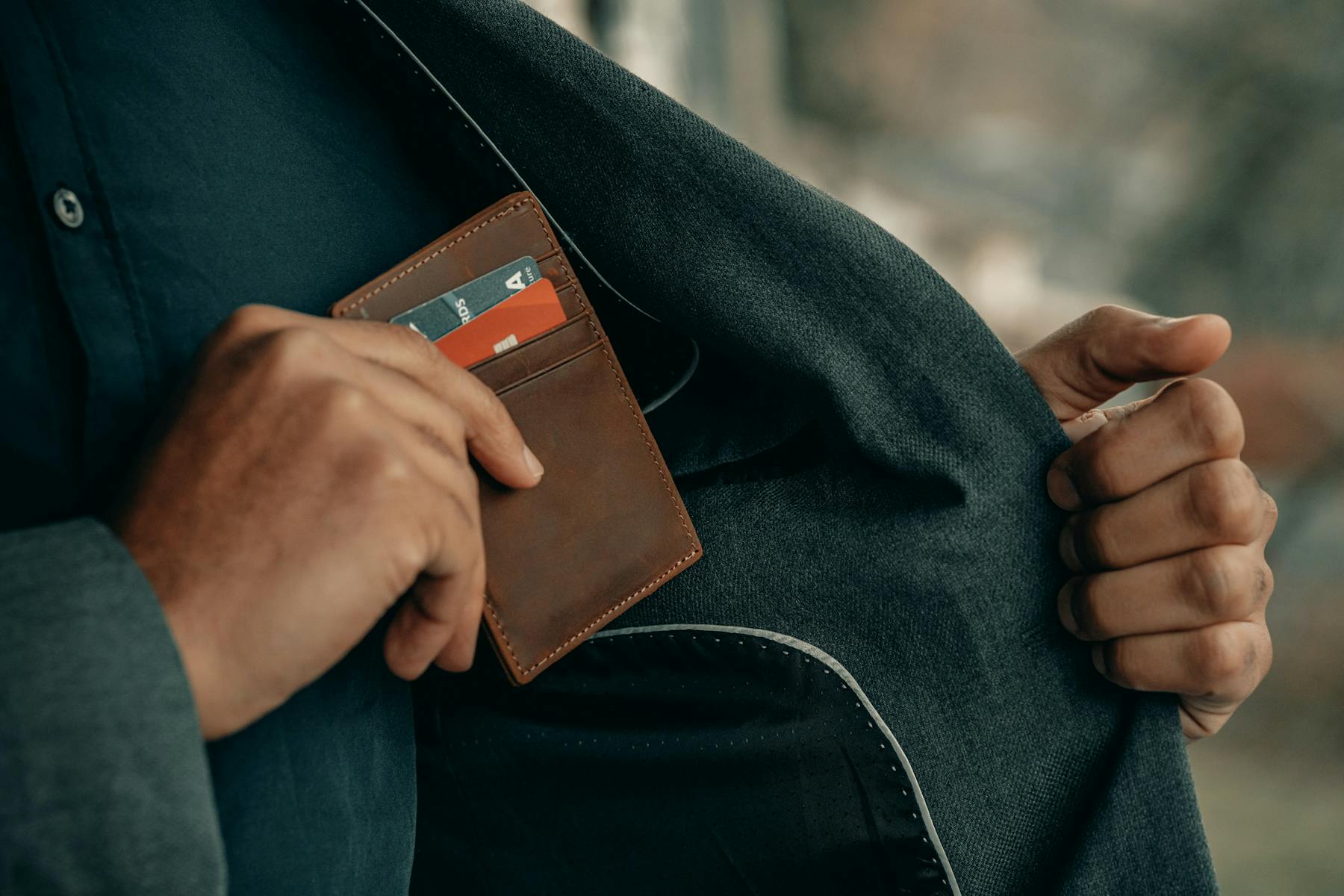 hombre guardando porta tarjetas de credito con 2 tarjetas en su chaqueta