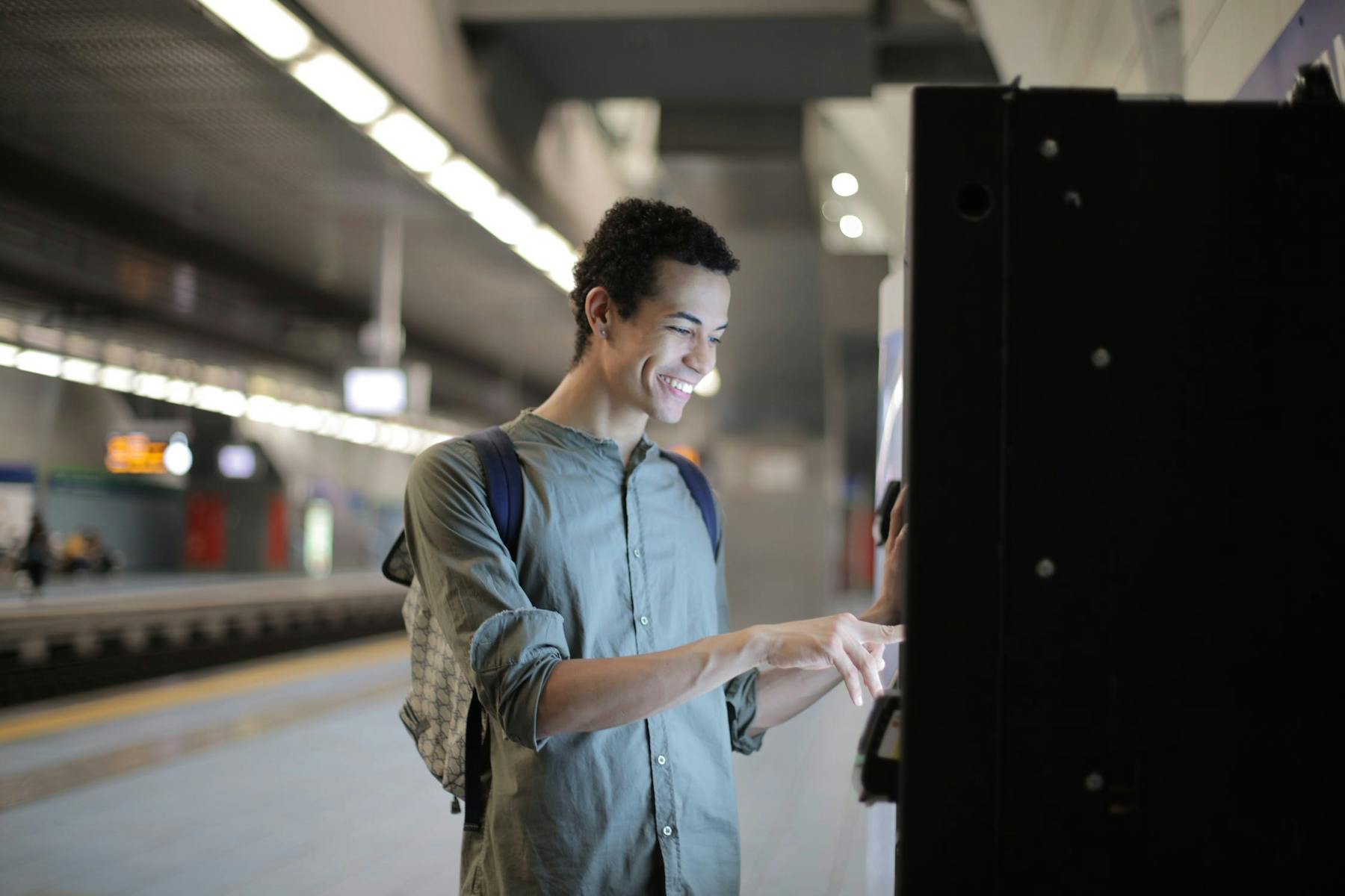 Homem sorridente realiza saque sem cartão no caixa automático do metrô