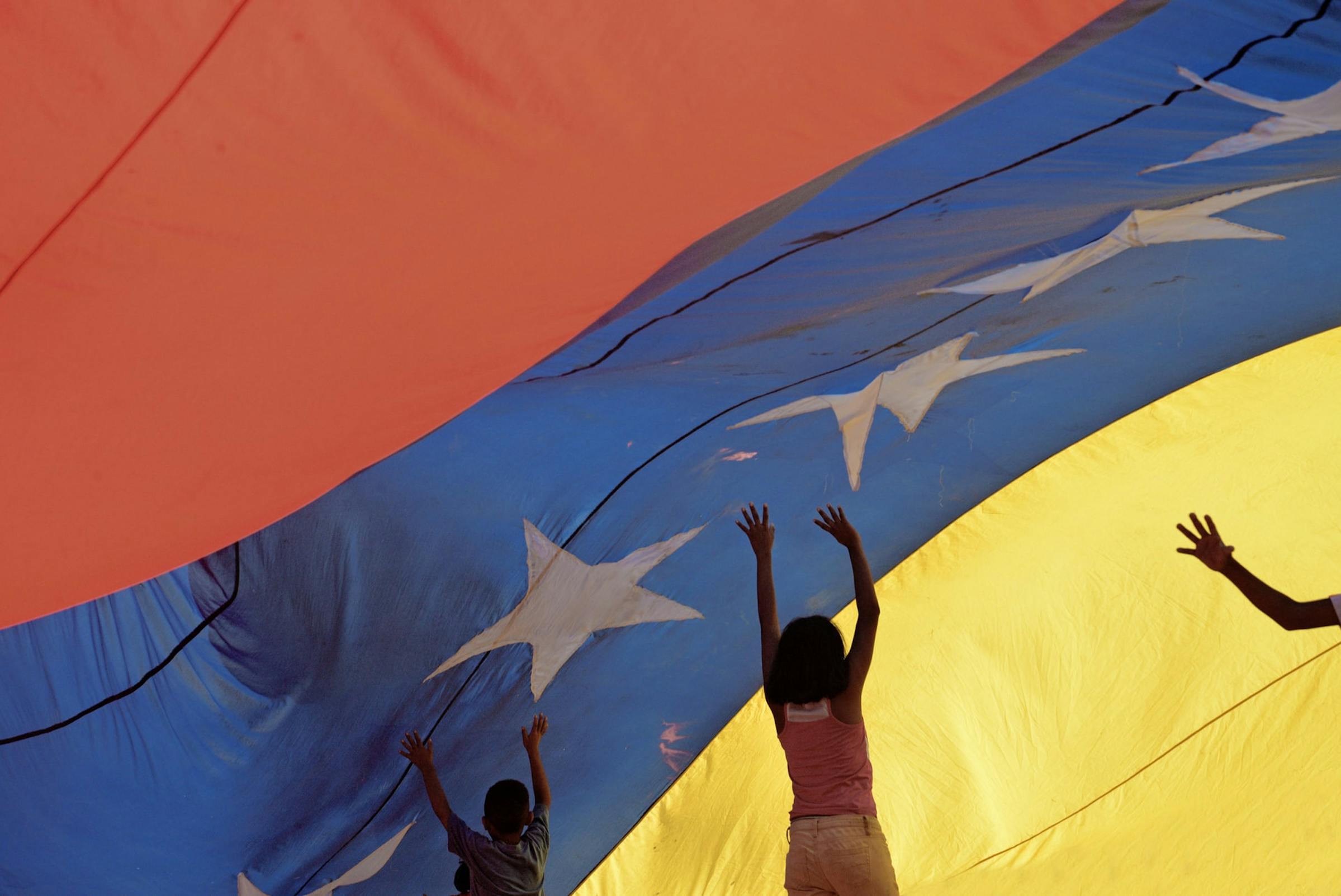 bandera de venezuela y niños tocando la bandera