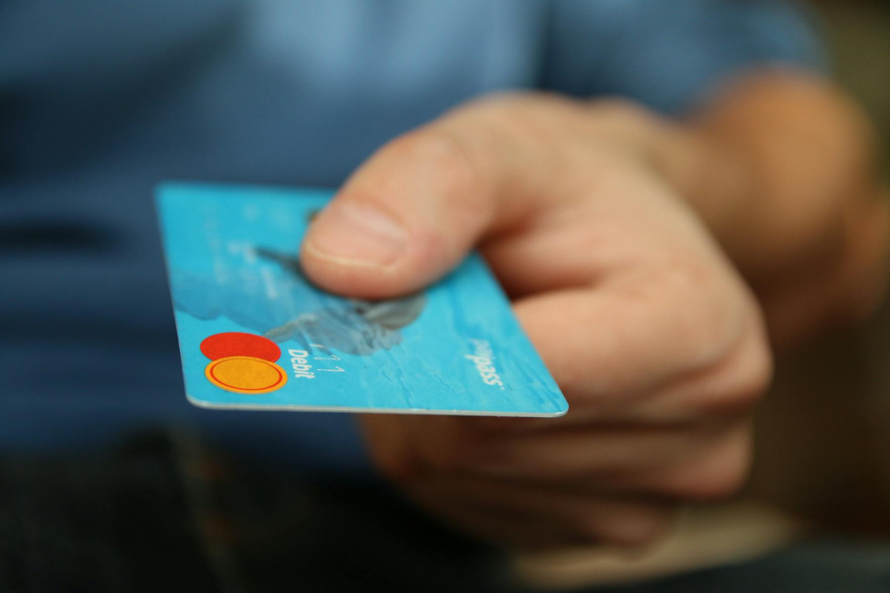 A person's hand holding a blue debit card