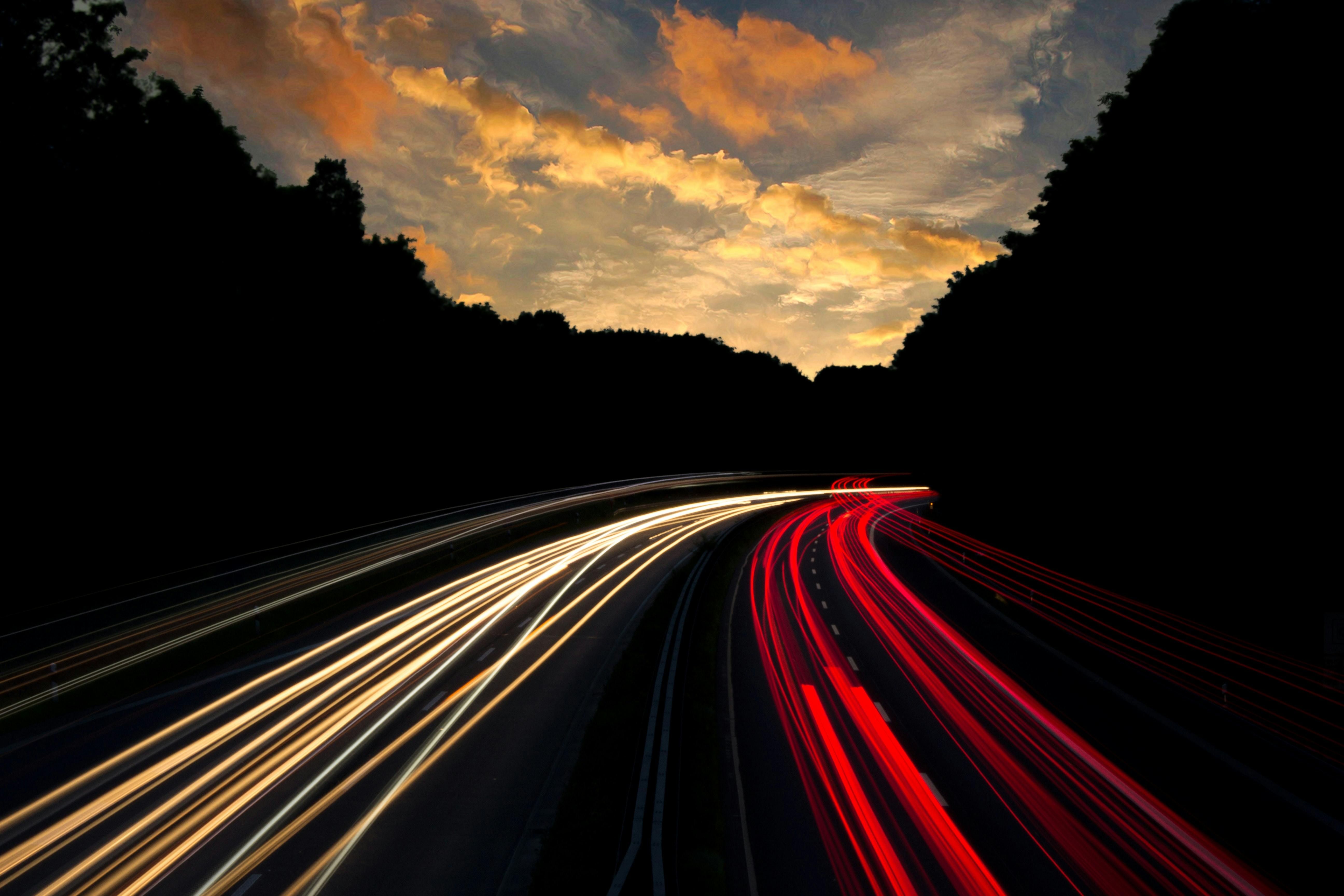 time lapse of a busy highway underneath a sunset sky