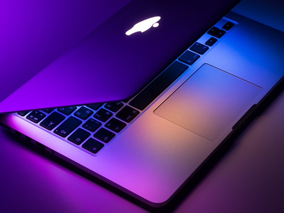 Apple laptop lit in purple and orange