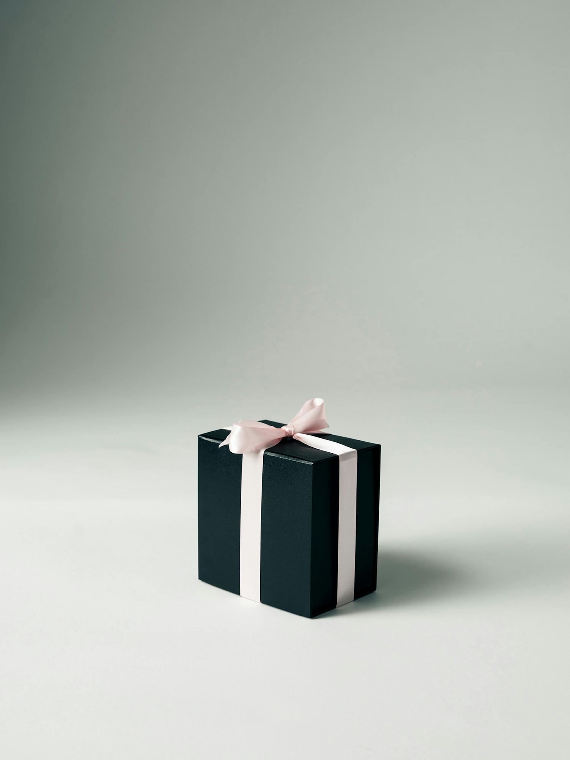 Schwarze Geschenkbox mit rosa Schleife auf weißem Hintergrund