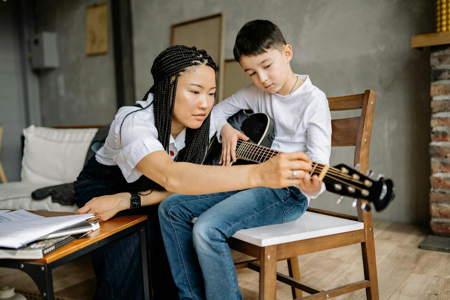 A teacher teaching a student finger placement on a guitar