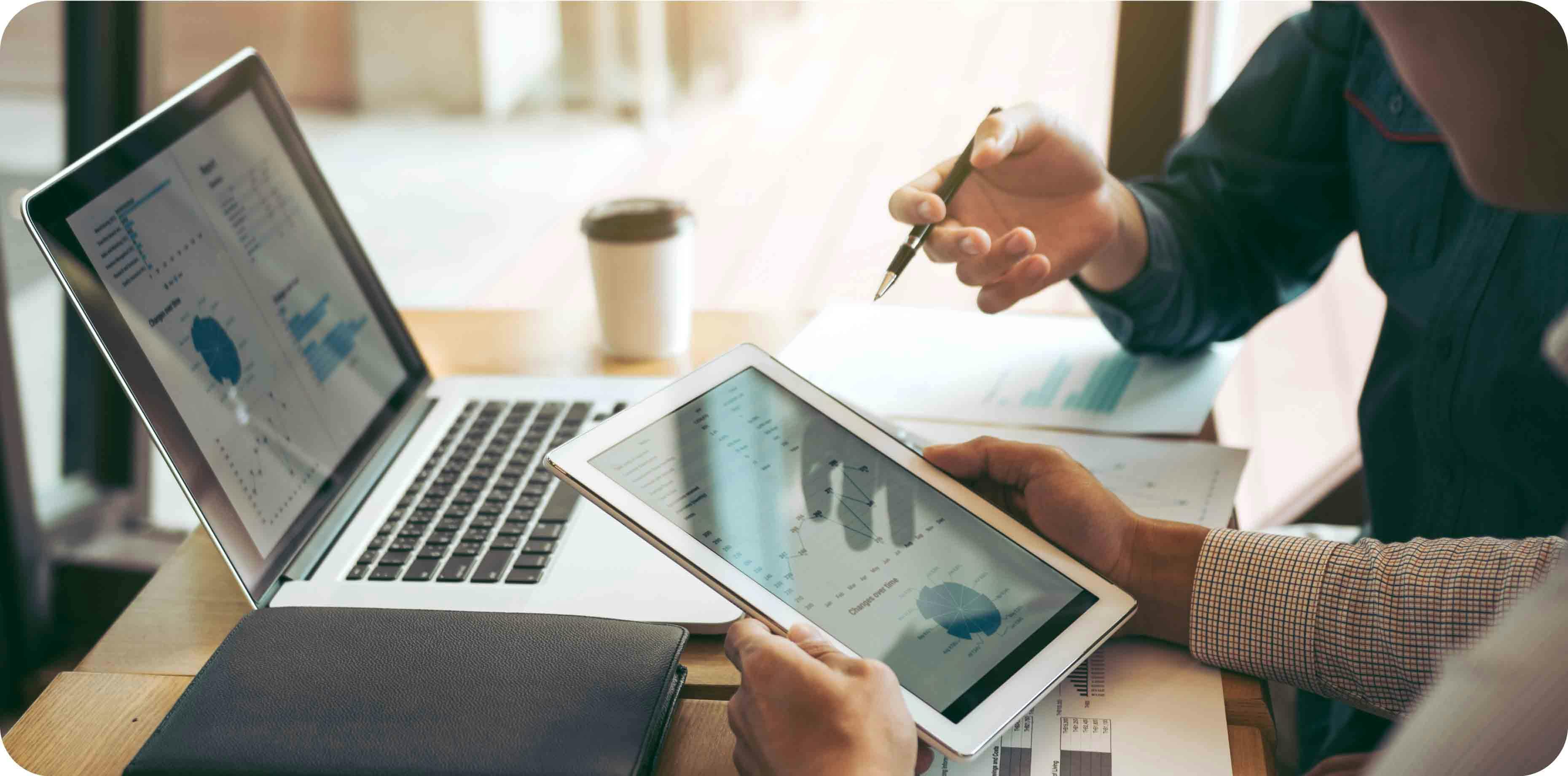 Two people having a business conversation using a laptop and a tablet