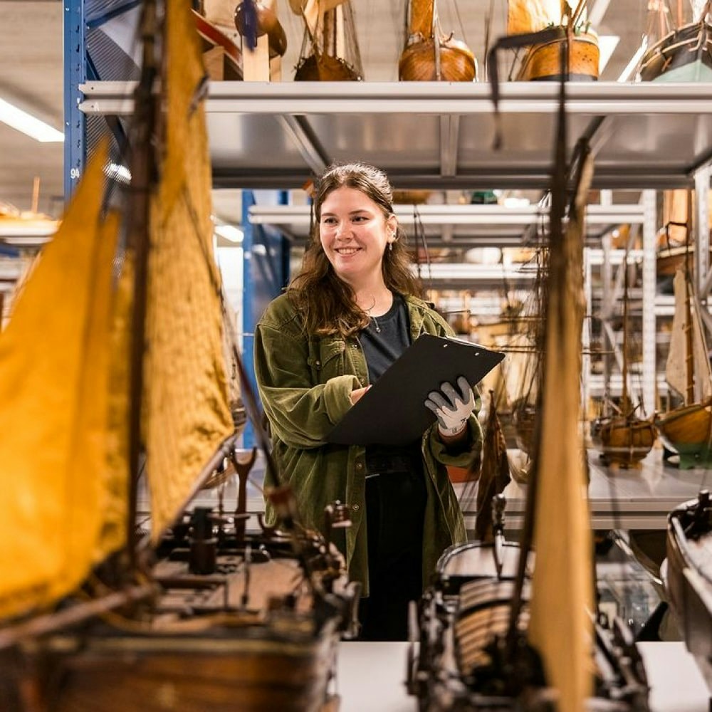 A person smiling and taking notes inside the Scheepvaart Museum in Amsterdam