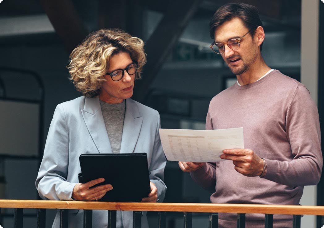 Two people discuss work over their notes