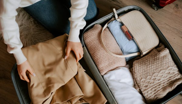 Someone packing up a travel suitcase