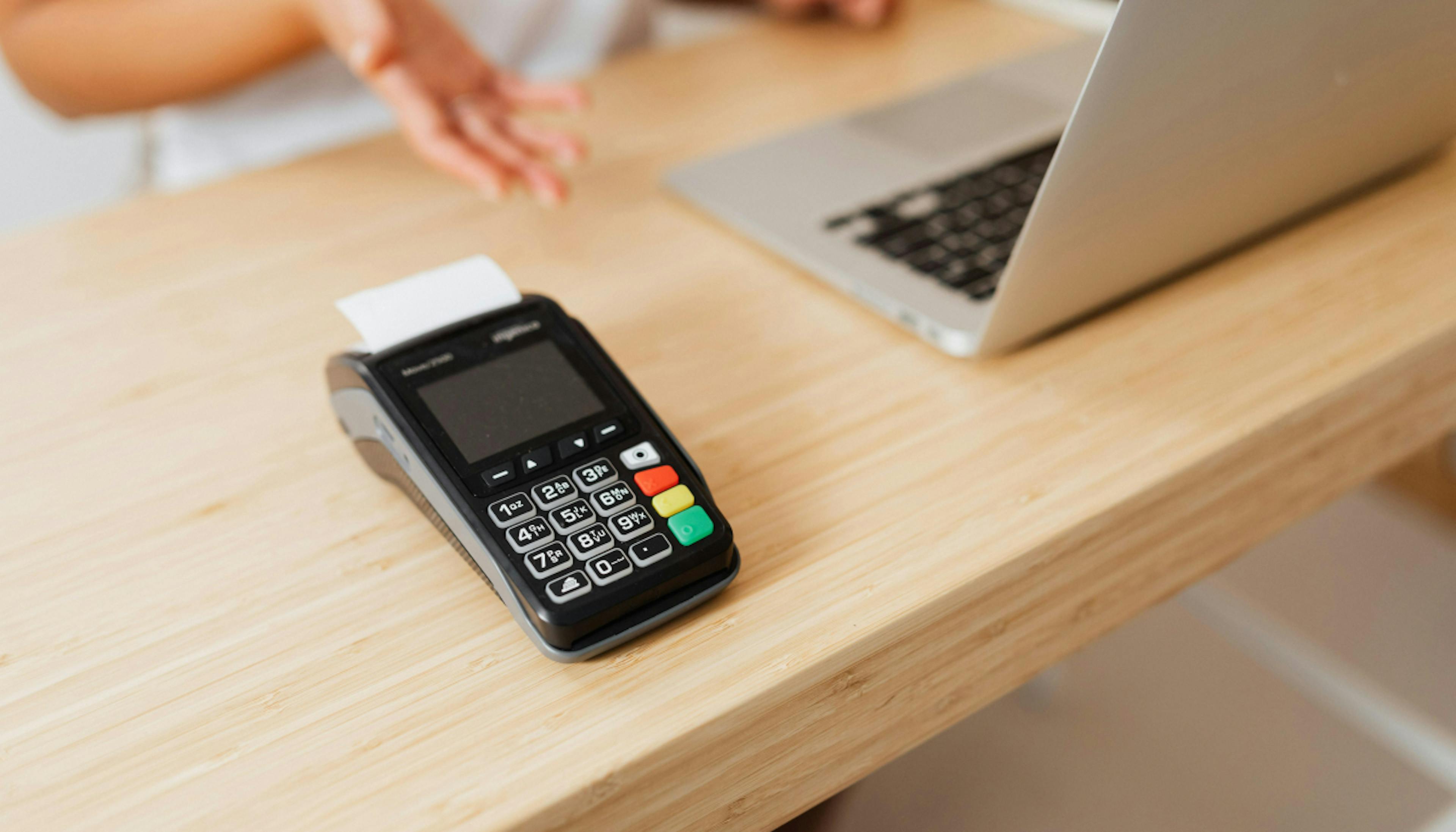 A POS terminal in a desk with a laptop