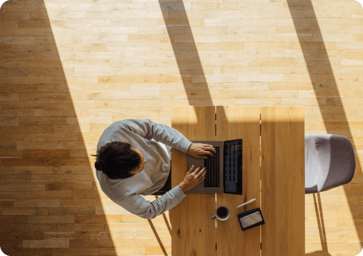 Een man zit aan een bureau en werkt op zijn laptop