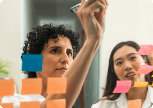 Two women writing on colourful post-its