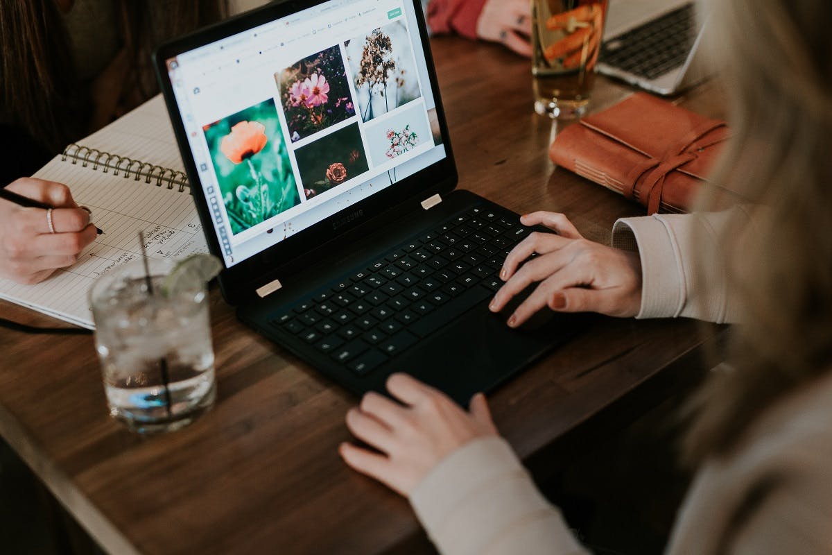 A lady using a laptop in a cafe. Ensure your nest laptop is both sustainable and ethical.