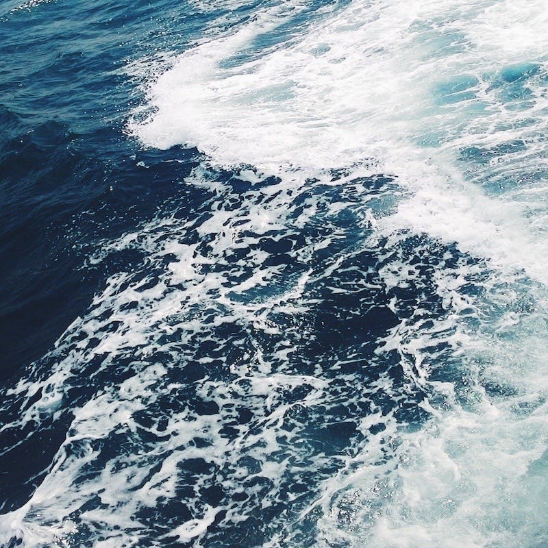 Frothy white waves are pictured on the surface of a deep blue ocean. 