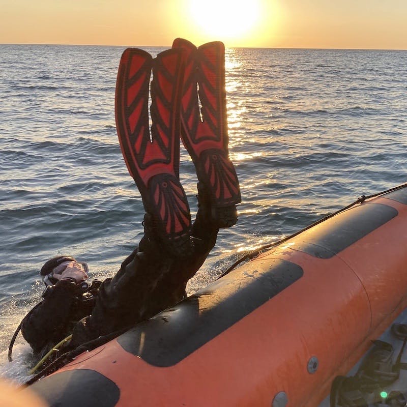 A scuba diver diving into the ocean from a rib.