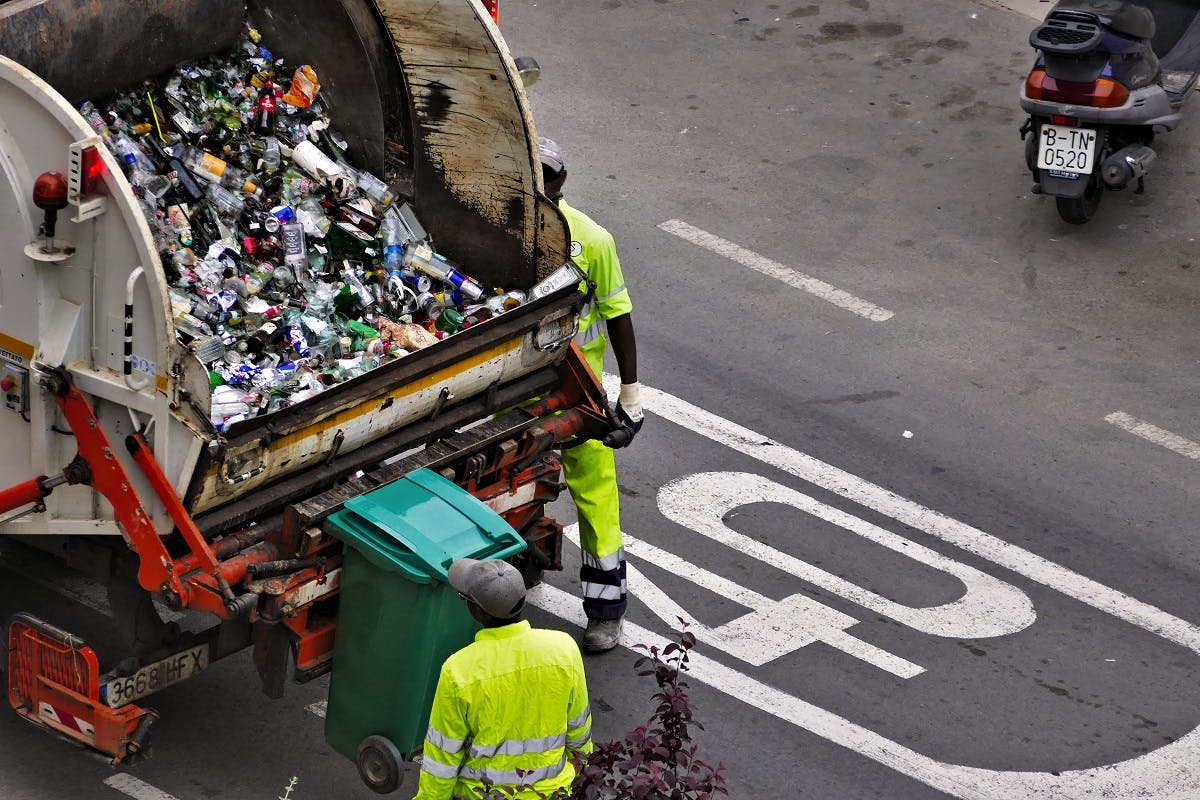 A dustbin lorry collecting recyclable glass bottles.