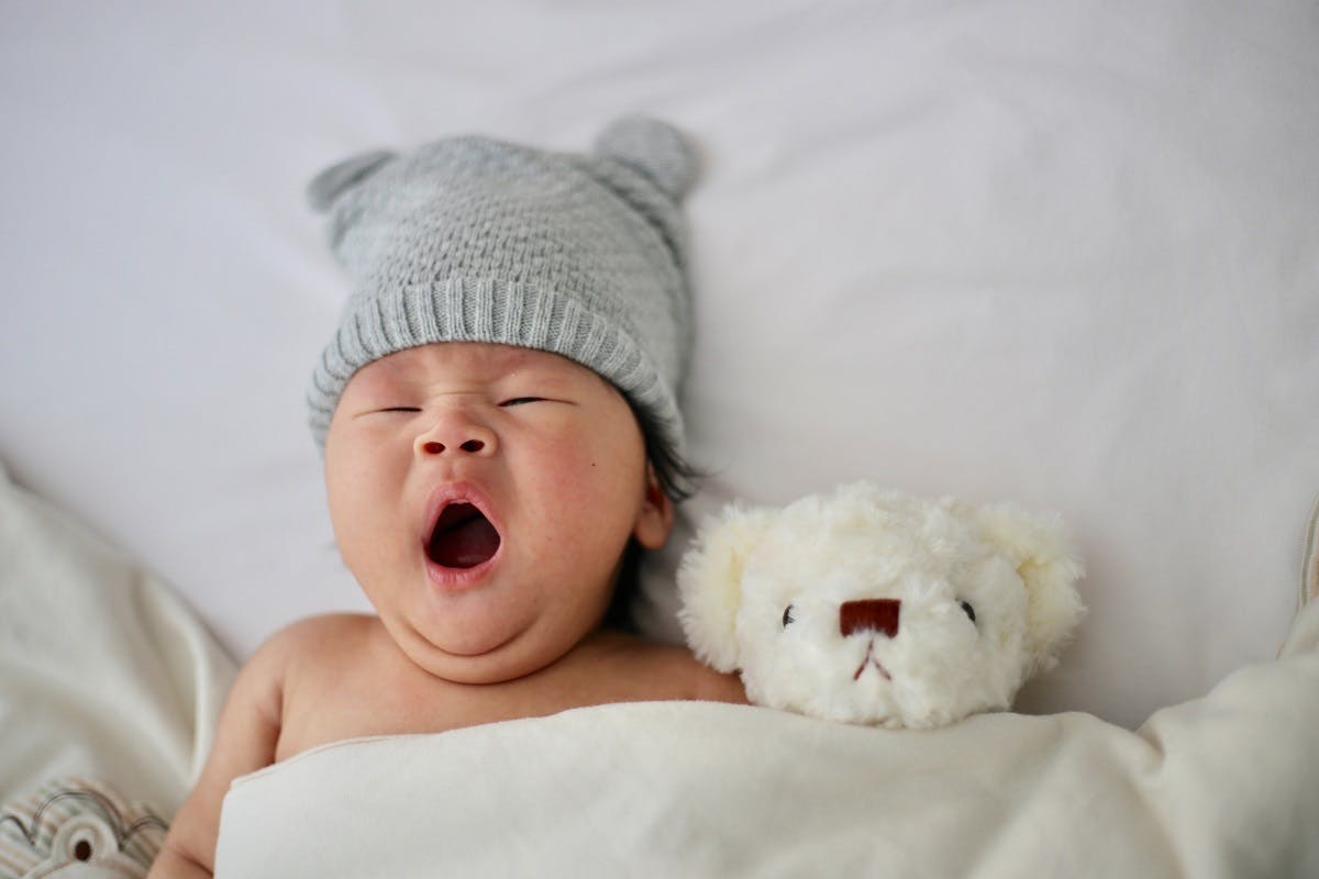 A baby sleeping next to its teddy. Cotton reusables ensure a better night's sleep for your eco baby