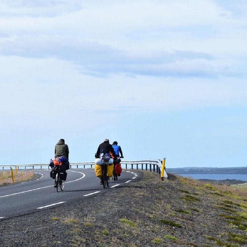 Three guys on travelling by bicycle passing beautiful lakes and mountains. Such slow travel is one of the biggest advantages to travelling without flying. 