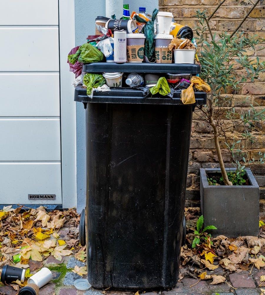 A wheely bin overflowing with packaging waste.