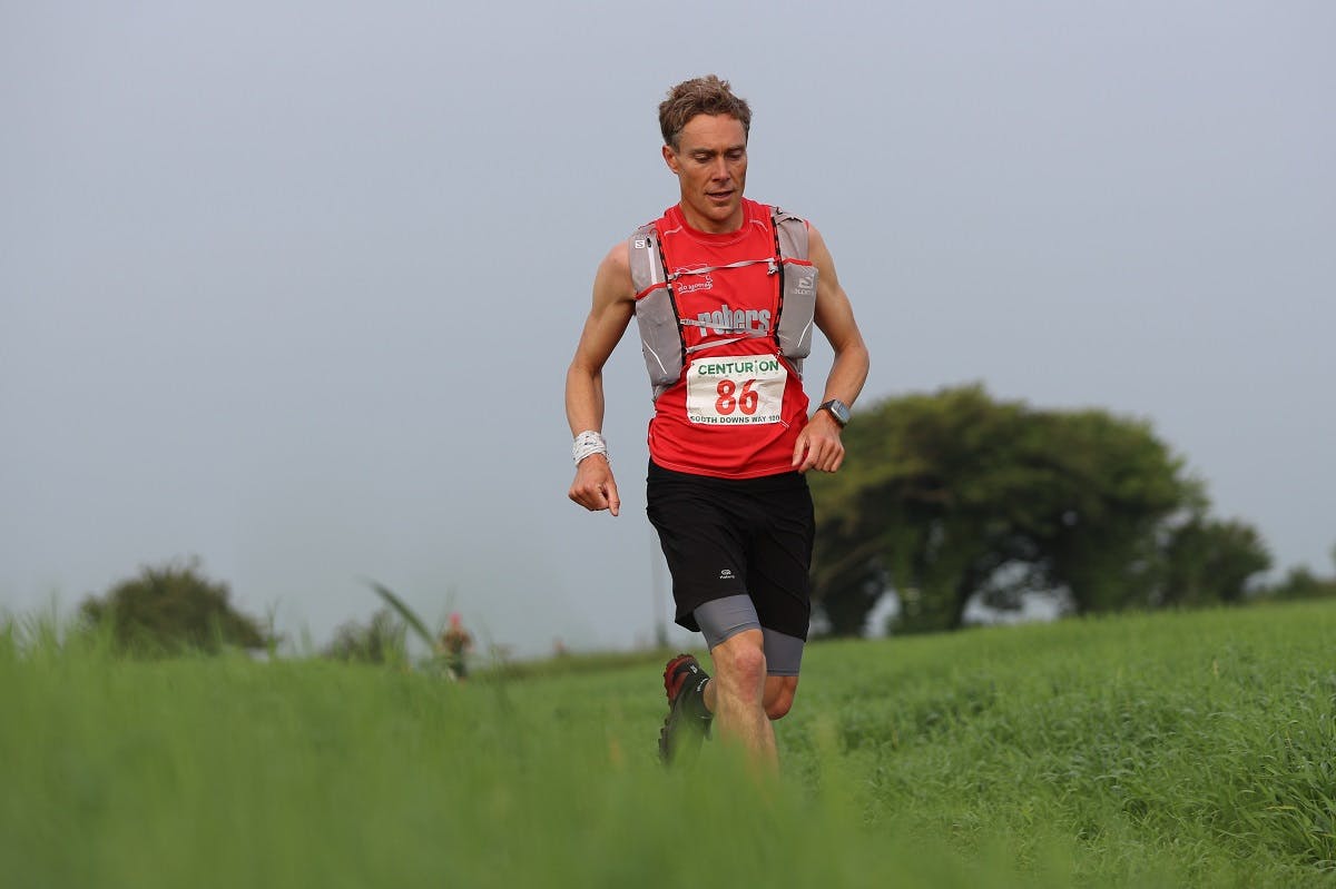 Going vegan doesn't mean you'll lack energy. Here, a plant based ultra trail marathon runner passing over a grassy hill.