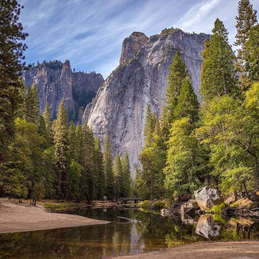 A calm stream meanders through a forest towards the step mountainsides. Healthy, rewilded, functioning ecosystems can provide us with a variety products and services that we depend on