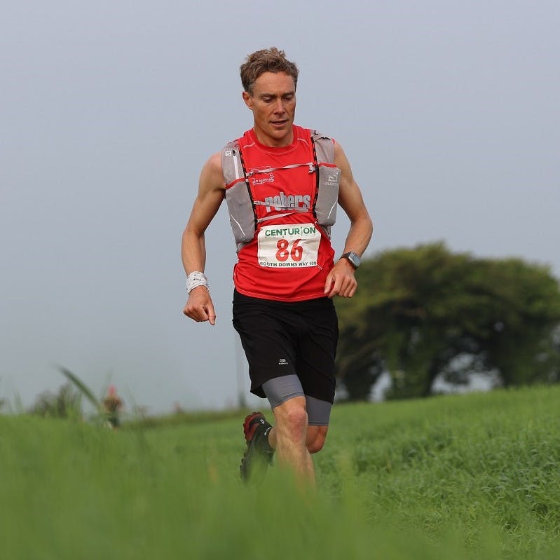 Going vegan doesn't mean you'll lack energy. Here, a plant based ultra trail marathon runner passing over a grassy hill. 