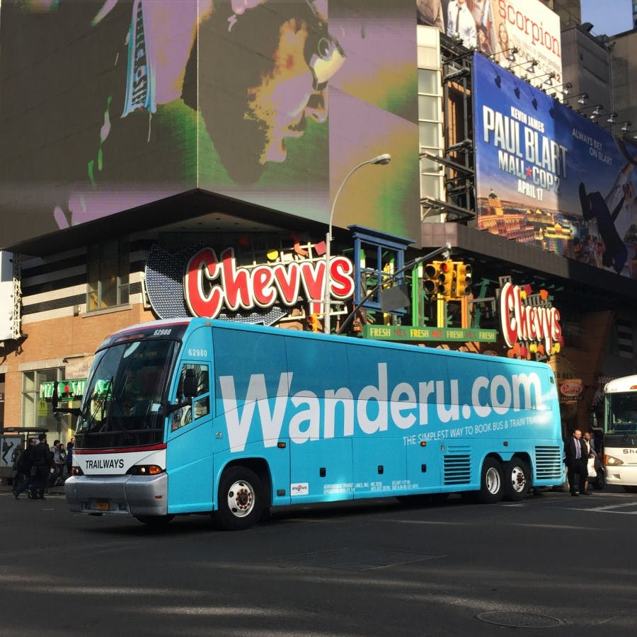 A Wanderu bus passes through a city centre. 