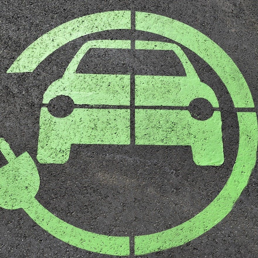 A green electric charging point sign painted on the tarmac.