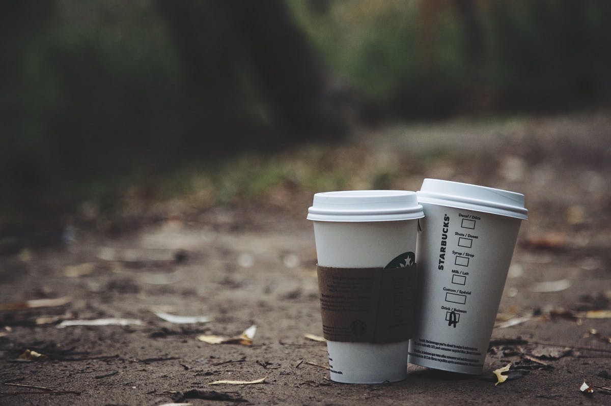 Take away Starbucks's coffee cups left on a table. Investing in a reusable coffee cup is an easy win on living plastic free 