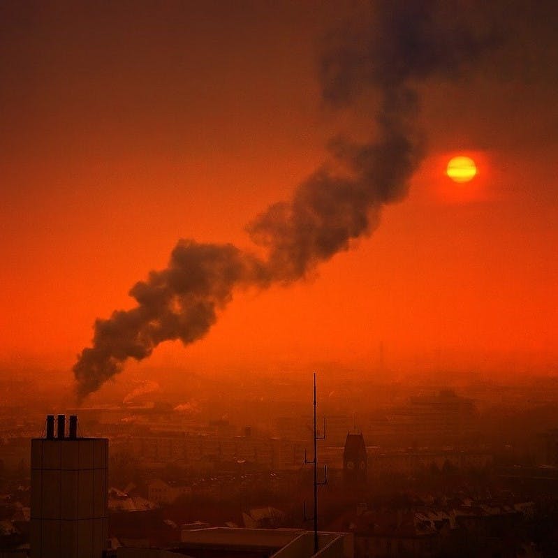 A fume of smoke rises into the air in a polluted city.