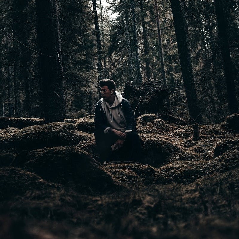 A man listening to a rewilding podcast in the woods
