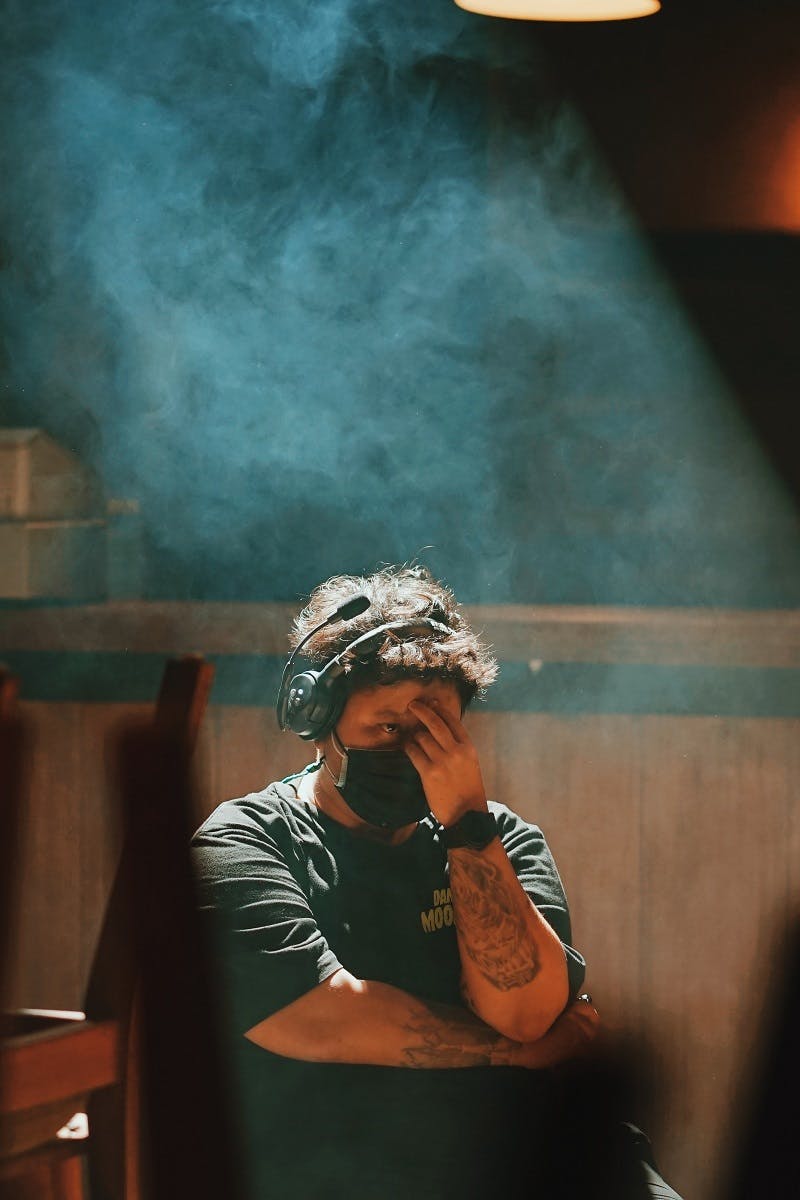 A stressed remote-worker wearing a mask and headset during the COVID-19 pandemic.