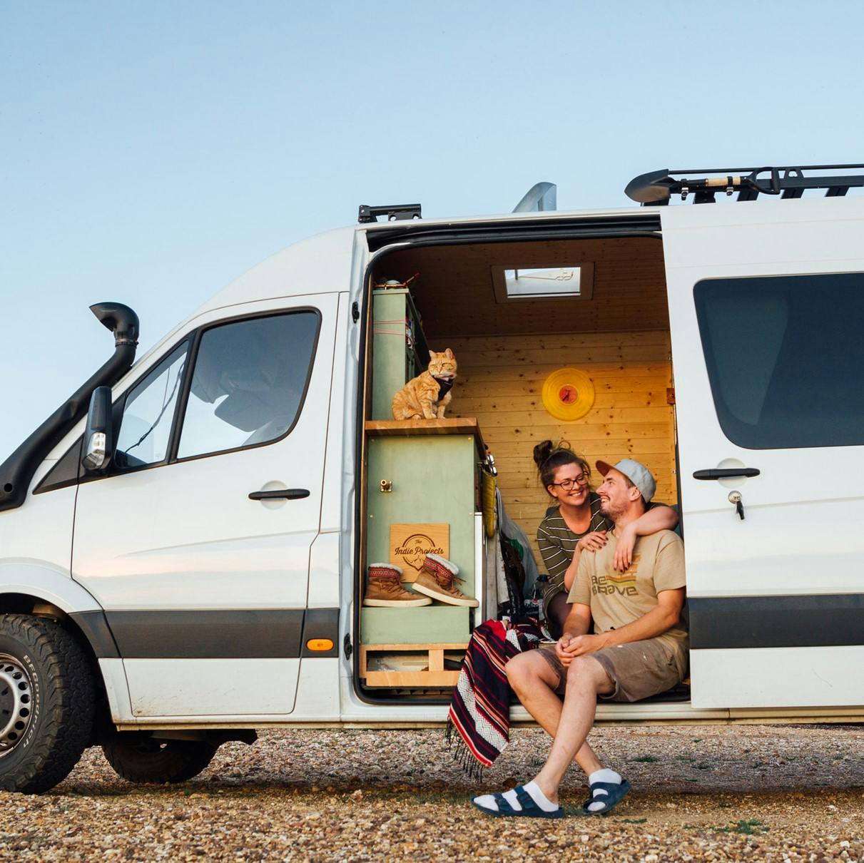 A couple and their cat on the road in their van.